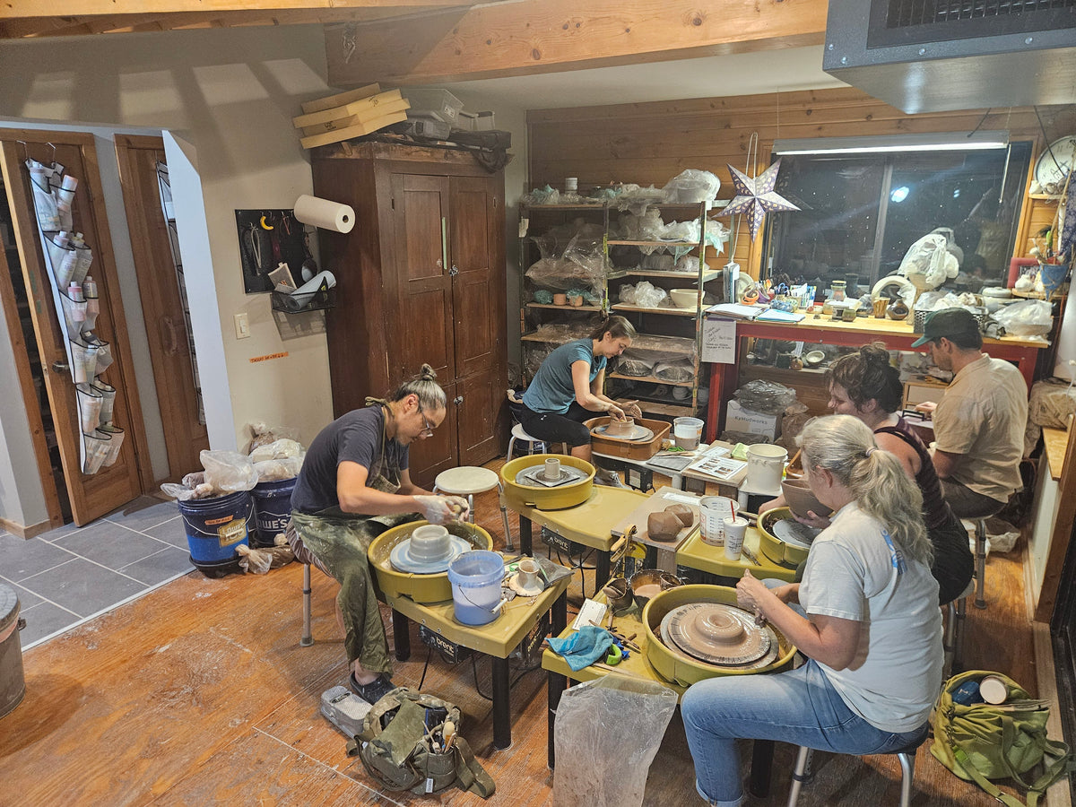 Five students at their wheels in the studio during an evening class